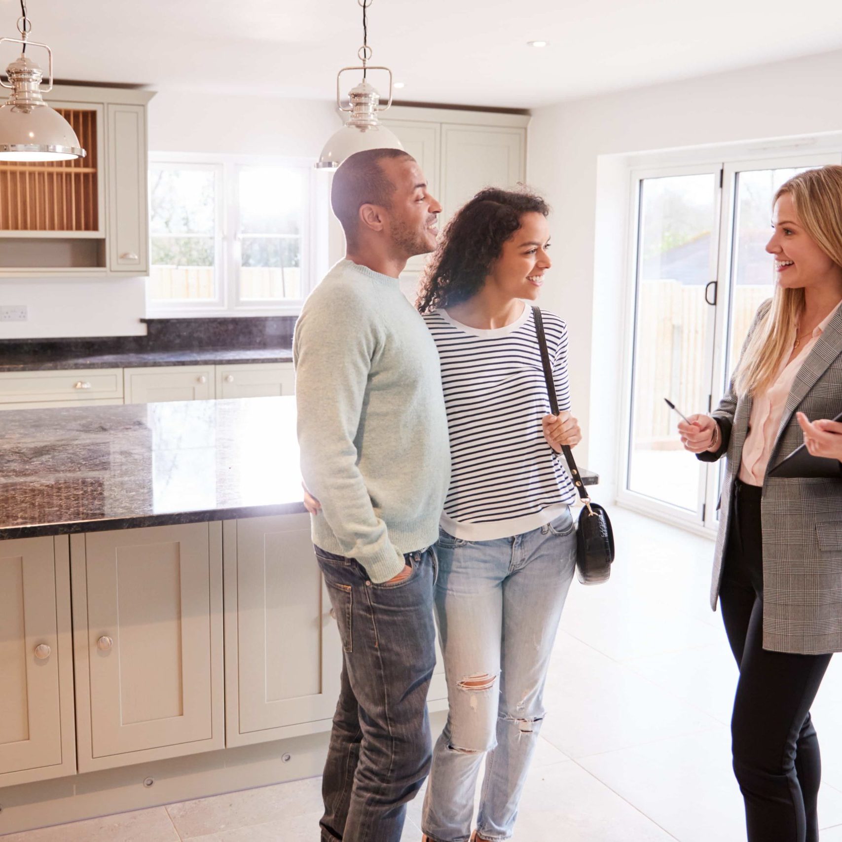 Female Realtor Showing Couple Interested In Buying Around House